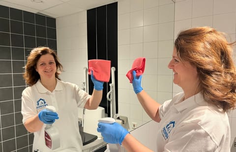 Medarbetare från Primus Städ putsar en badrumsspegel